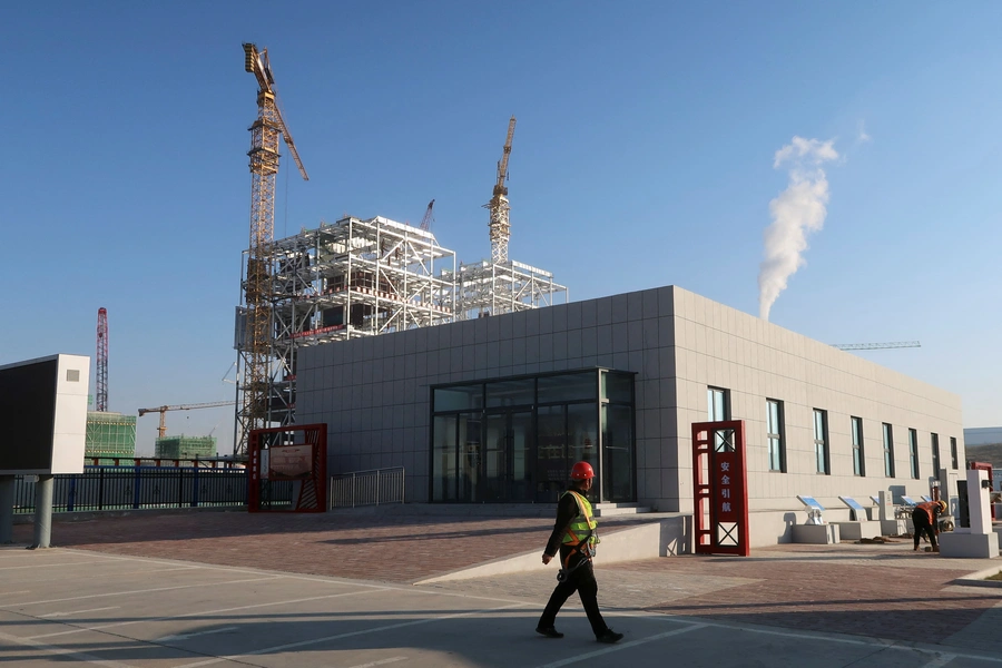 Worker walks past cranes at Yushen Yuheng power plant, a coal-fired power plant under construction, in Yulin City, Guangxi Zhuang Autonomous Region, People's Republic of China.